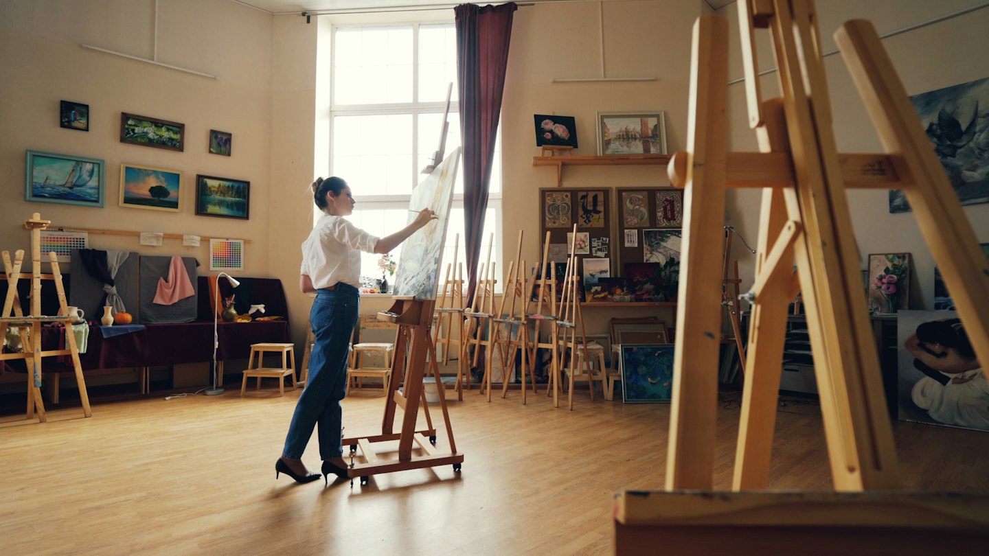 Woman painting a large canvas in a bright art studio.