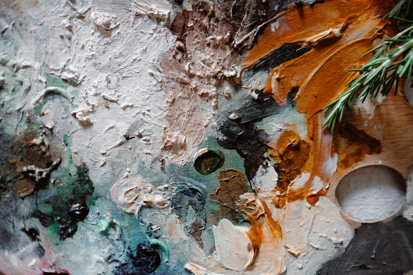 Artist's palette with colorful oil paints and rosemary sprig.