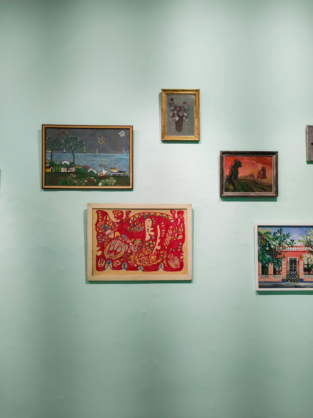 Framed paintings displayed on a light mint green wall.